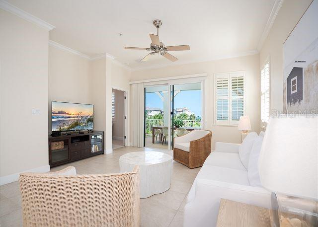 tiled living room featuring crown molding and ceiling fan