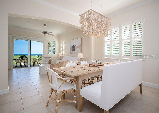 tiled dining room featuring ornamental molding and ceiling fan with notable chandelier