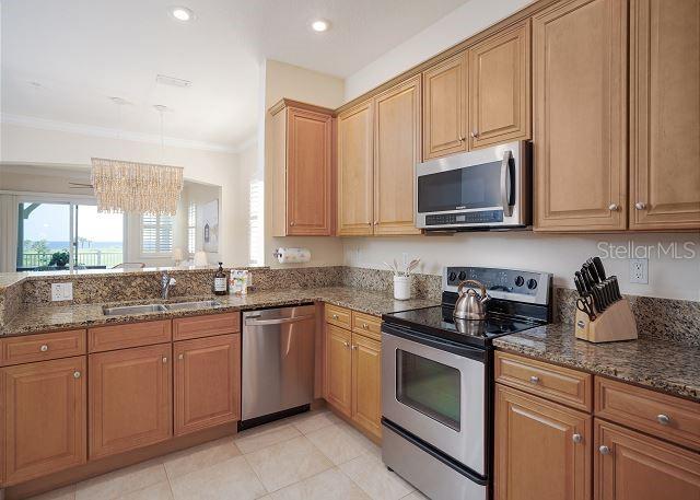 kitchen with stainless steel appliances, sink, hanging light fixtures, and dark stone counters