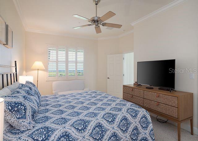 carpeted bedroom with ornamental molding and ceiling fan