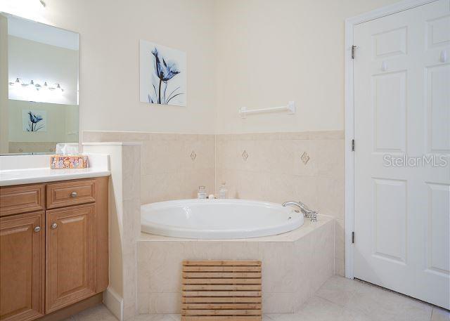 bathroom featuring vanity, tiled tub, and tile patterned floors