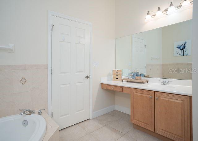 bathroom with tile patterned flooring, vanity, and tiled bath