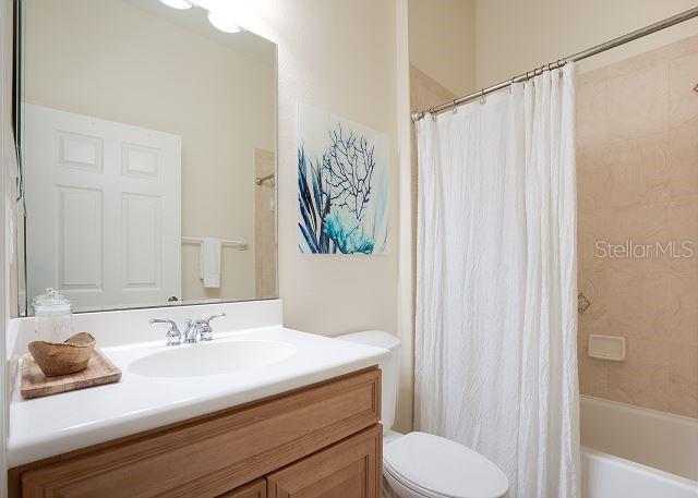 full bathroom featuring vanity, shower / bath combination with curtain, and toilet