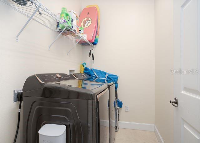 laundry room with washing machine and dryer and light tile patterned floors