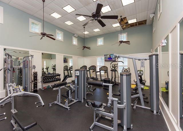 exercise room with a high ceiling, a drop ceiling, and ceiling fan