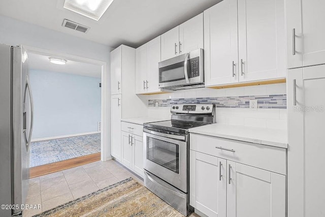 kitchen with tasteful backsplash, white cabinetry, appliances with stainless steel finishes, and light tile patterned floors