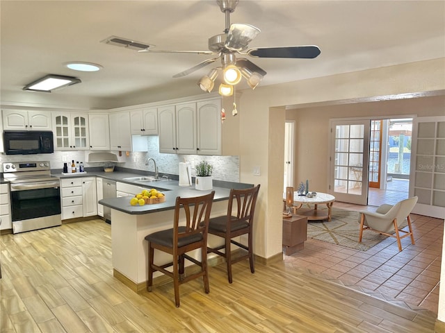 155 Avalon Ave, Flagler Beach, FL 32136 - kitchen with appliances with stainless steel finishes, sink, white cabinets, backsplash, and kitchen peninsula