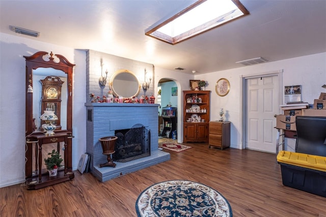 living room featuring dark hardwood / wood-style floors, a fireplace, and a skylight