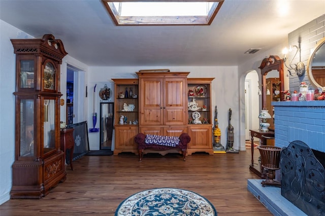 living area featuring a fireplace, dark hardwood / wood-style flooring, and a skylight