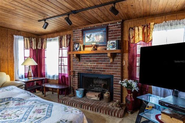 bedroom featuring wood ceiling, wooden walls, carpet, a fireplace, and track lighting