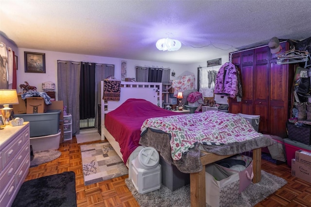 bedroom featuring parquet floors, radiator, and a textured ceiling