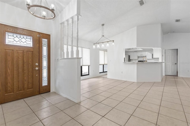 foyer with vaulted ceiling, light tile patterned flooring, a chandelier, and visible vents