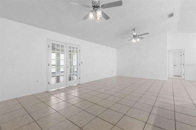empty room featuring a ceiling fan, visible vents, light tile patterned flooring, vaulted ceiling, and a textured ceiling