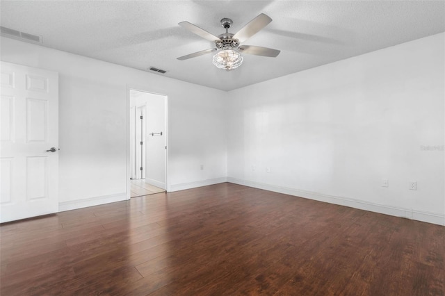 empty room featuring a ceiling fan, wood finished floors, visible vents, and a textured ceiling