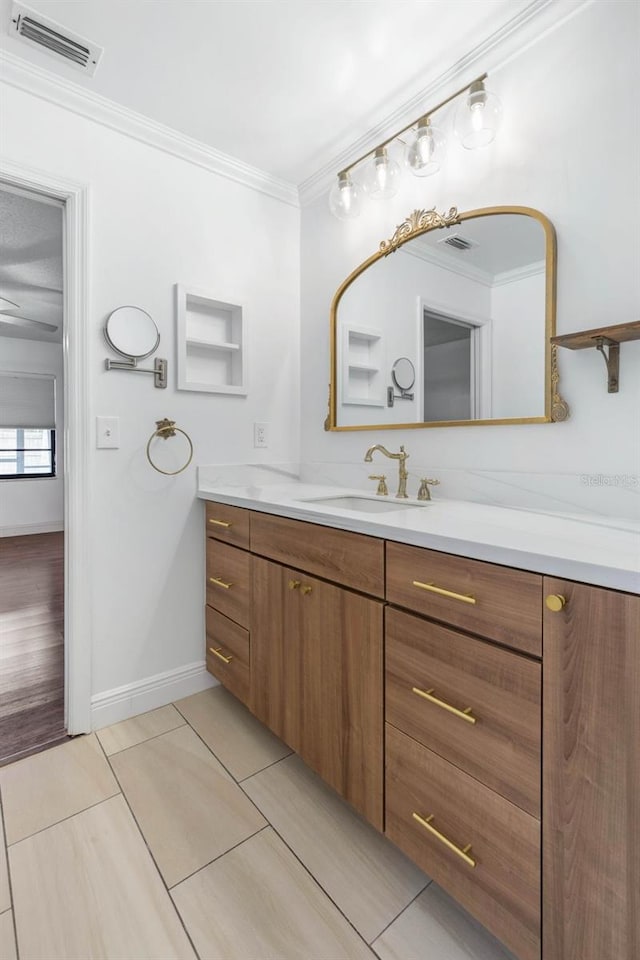 bathroom featuring vanity, crown molding, baseboards, and visible vents