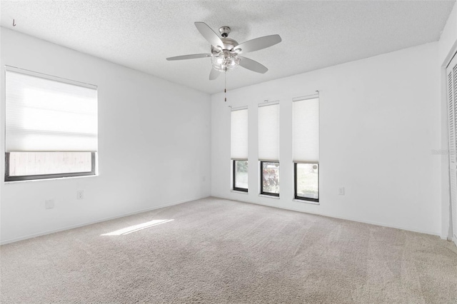 unfurnished room featuring plenty of natural light, ceiling fan, and carpet floors