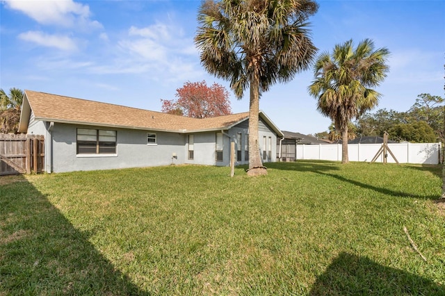 back of property featuring a yard, stucco siding, and a fenced backyard