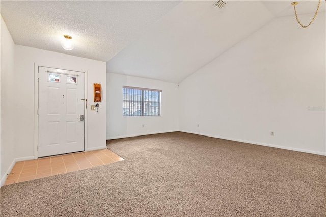 foyer entrance with lofted ceiling, light colored carpet, and a textured ceiling