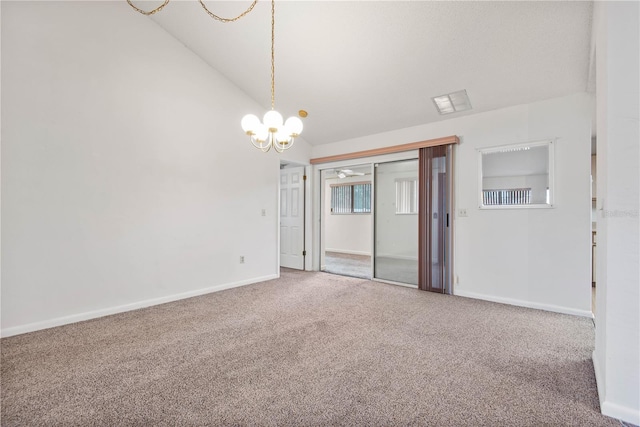 carpeted empty room with a notable chandelier and vaulted ceiling