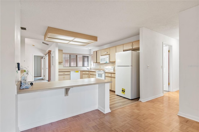 kitchen with sink, a kitchen breakfast bar, kitchen peninsula, light parquet flooring, and white appliances