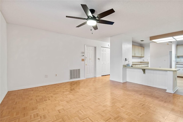 unfurnished living room featuring ceiling fan, a textured ceiling, and light parquet floors