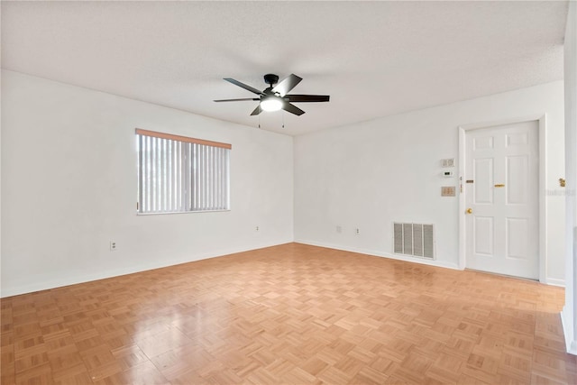 unfurnished room featuring ceiling fan, light parquet flooring, and a textured ceiling