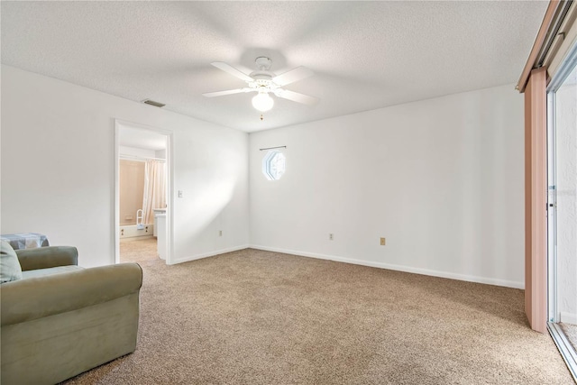 living area featuring ceiling fan, light colored carpet, and a textured ceiling