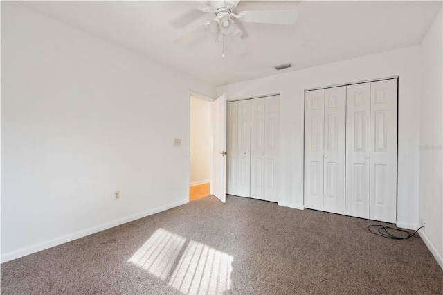 unfurnished bedroom with multiple closets, carpet flooring, and ceiling fan