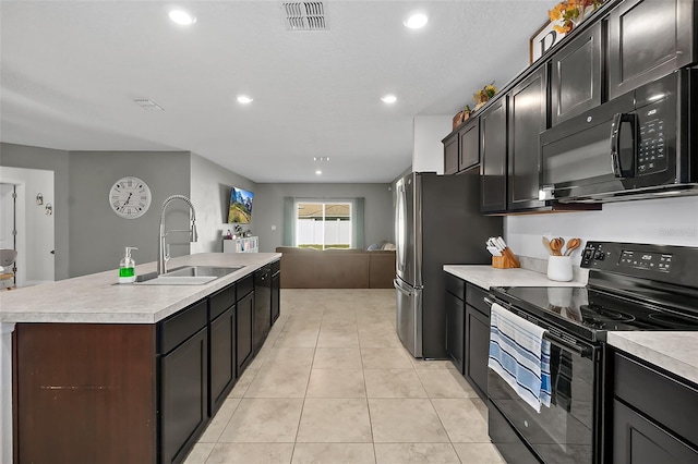 kitchen with an island with sink, sink, light tile patterned floors, and black appliances