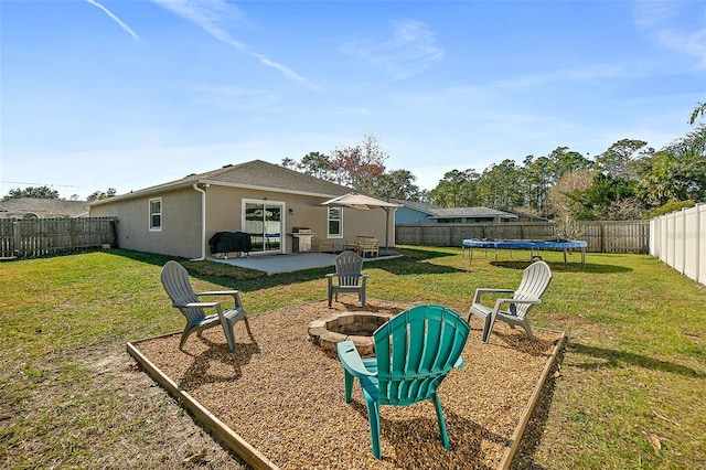 view of yard with a trampoline, a fire pit, and a patio area