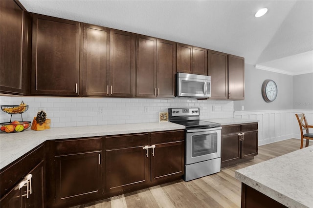 kitchen featuring tasteful backsplash, appliances with stainless steel finishes, light wood-type flooring, and dark brown cabinetry