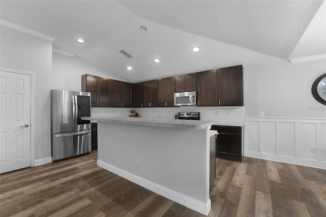 kitchen featuring appliances with stainless steel finishes, dark hardwood / wood-style floors, lofted ceiling, a center island, and dark brown cabinets