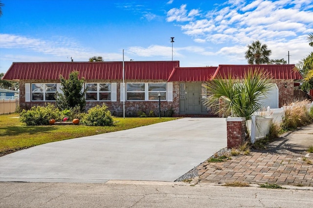 view of front of home featuring concrete driveway, brick siding, a front yard, and fence