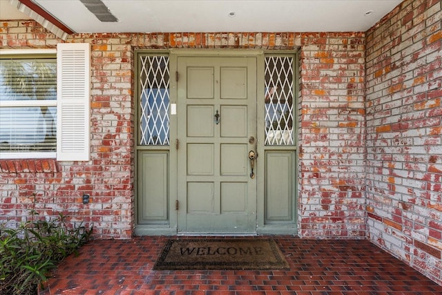 doorway to property featuring brick siding