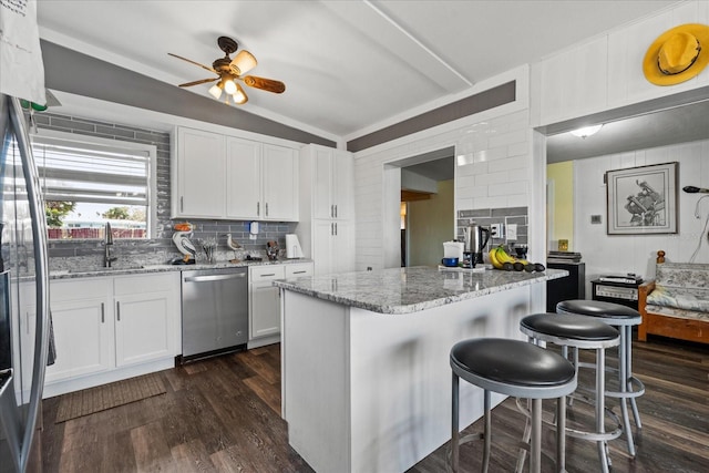 kitchen featuring decorative backsplash, dishwasher, a breakfast bar area, dark wood-type flooring, and white cabinetry