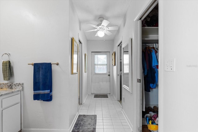 interior space with ceiling fan, vanity, baseboards, a spacious closet, and tile patterned floors