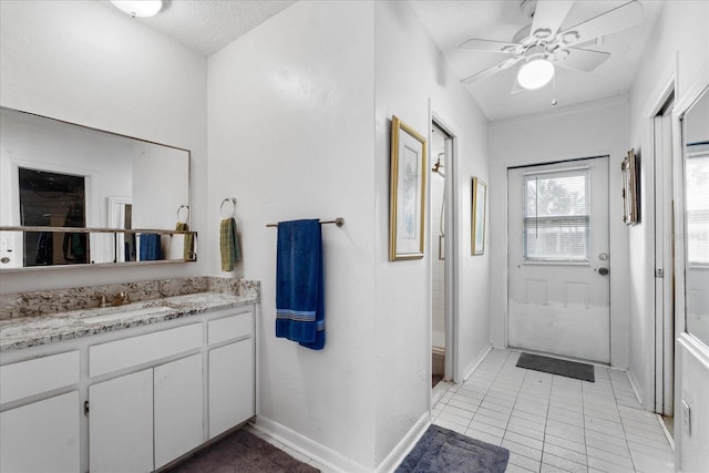 full bath with a textured ceiling, ceiling fan, vanity, baseboards, and tile patterned floors