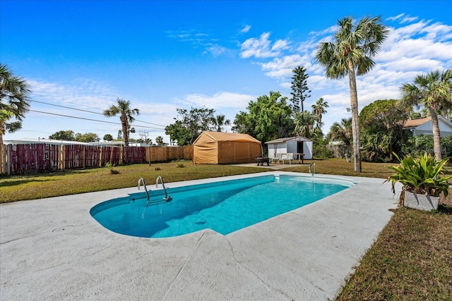 view of pool featuring a fenced in pool, an outbuilding, a yard, a patio area, and a fenced backyard