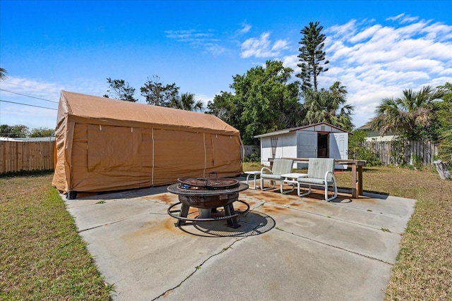 view of patio / terrace with an outdoor fire pit, fence, an outdoor structure, and a shed