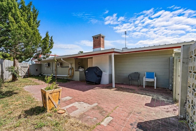 back of property featuring a chimney, a patio area, fence, and a gate