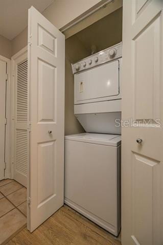 laundry room with stacked washer / drying machine and light wood-type flooring