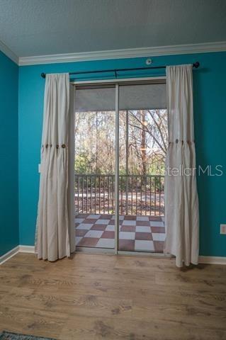 doorway featuring crown molding, plenty of natural light, and wood-type flooring