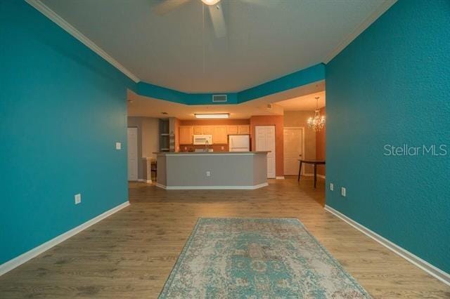 unfurnished living room with crown molding, ceiling fan with notable chandelier, and light hardwood / wood-style flooring