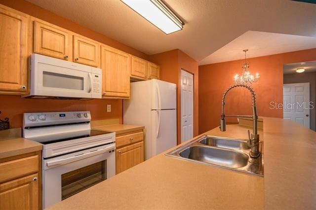 kitchen featuring white appliances, decorative light fixtures, light brown cabinetry, and sink