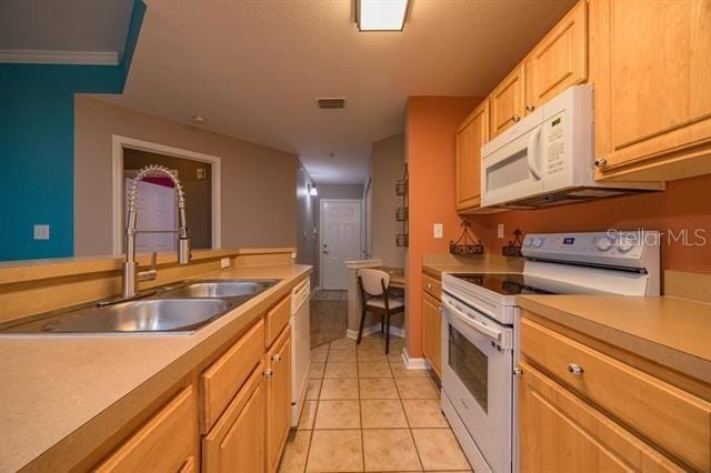 kitchen featuring light tile patterned flooring, white appliances, sink, and light brown cabinets