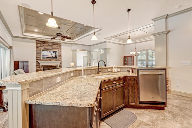 kitchen featuring sink, hanging light fixtures, stainless steel dishwasher, a raised ceiling, and decorative columns