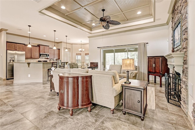 living room with a towering ceiling, ornamental molding, coffered ceiling, ceiling fan, and a raised ceiling