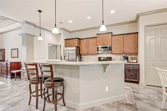 kitchen with pendant lighting, appliances with stainless steel finishes, a kitchen breakfast bar, and light stone counters