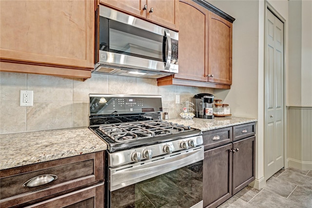 kitchen featuring stainless steel appliances, light stone countertops, and decorative backsplash