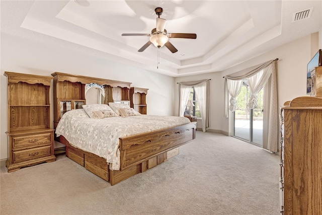 carpeted bedroom featuring access to exterior, a raised ceiling, and ceiling fan